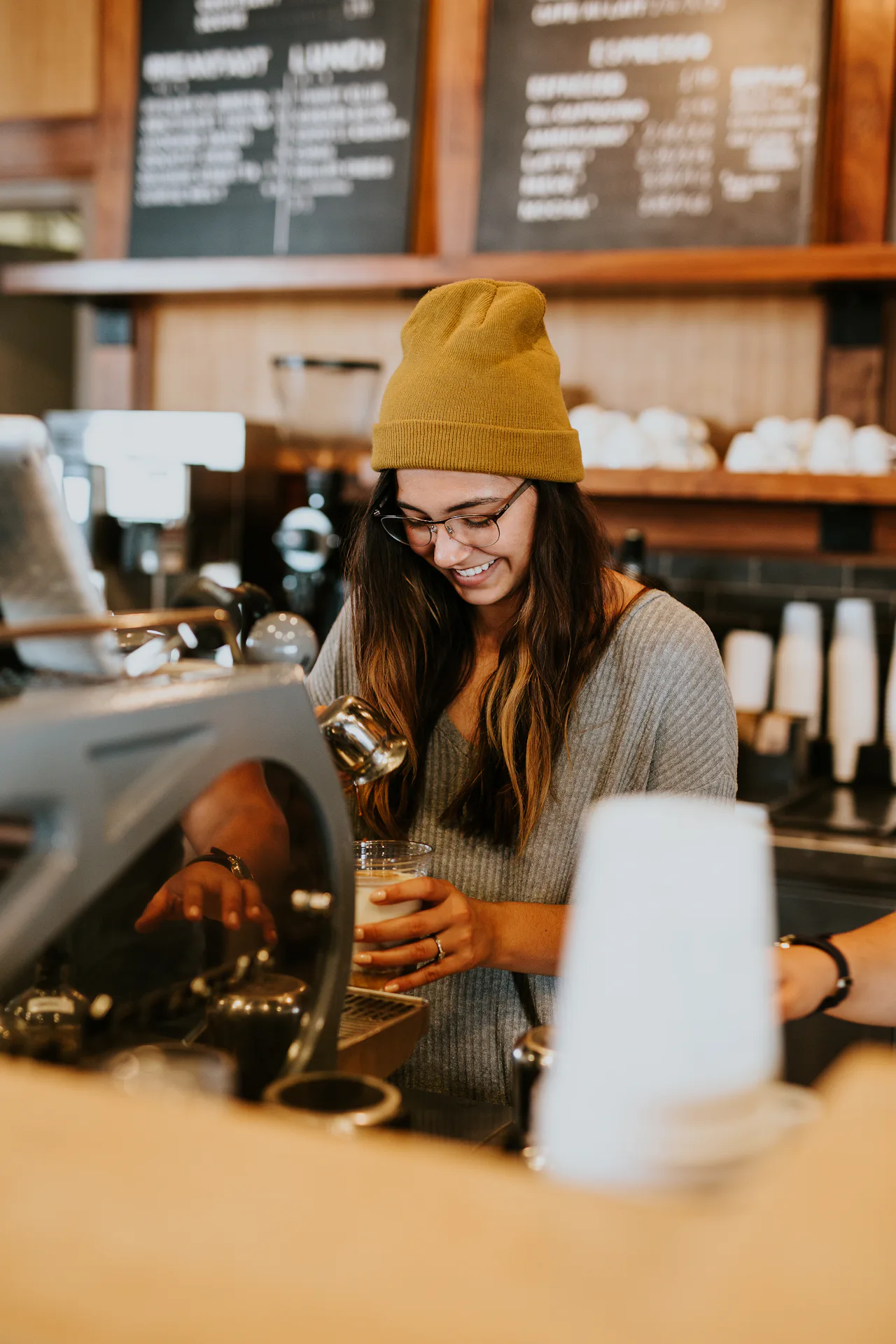 Barista zâmbind la bar, lângă espressor