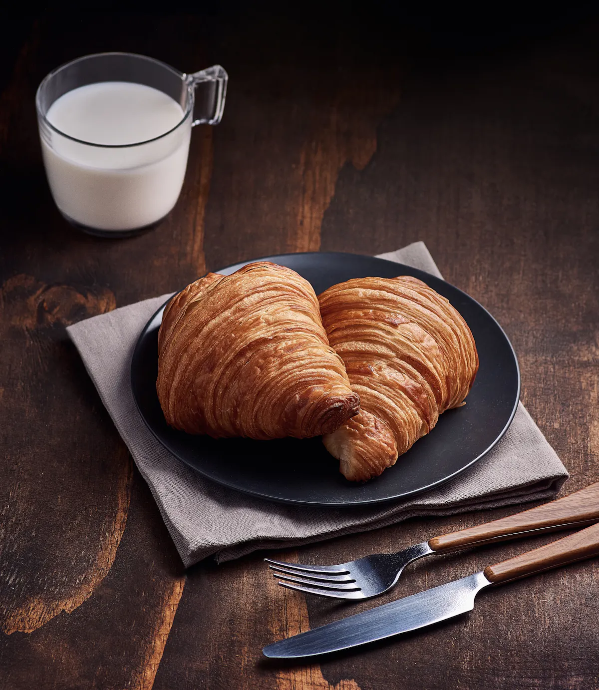 Două croissante proaspete pe o farfurie neagră